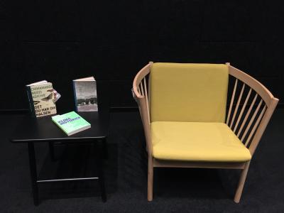 Et lille sort bord med tre noveller og en gul lænestol.